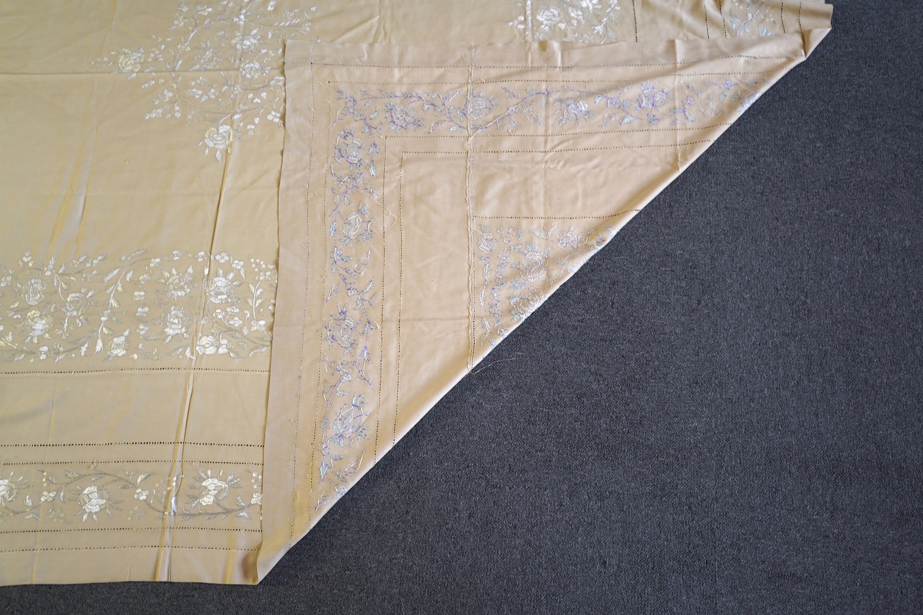 A 1920’s heavy shantung silk hand embroidered table cover. Worked with decorative rows of button hole stitch. Embroidered with white, green and blue silk flowers. 240cm x 204cm. Condition - some fine holes near corners,